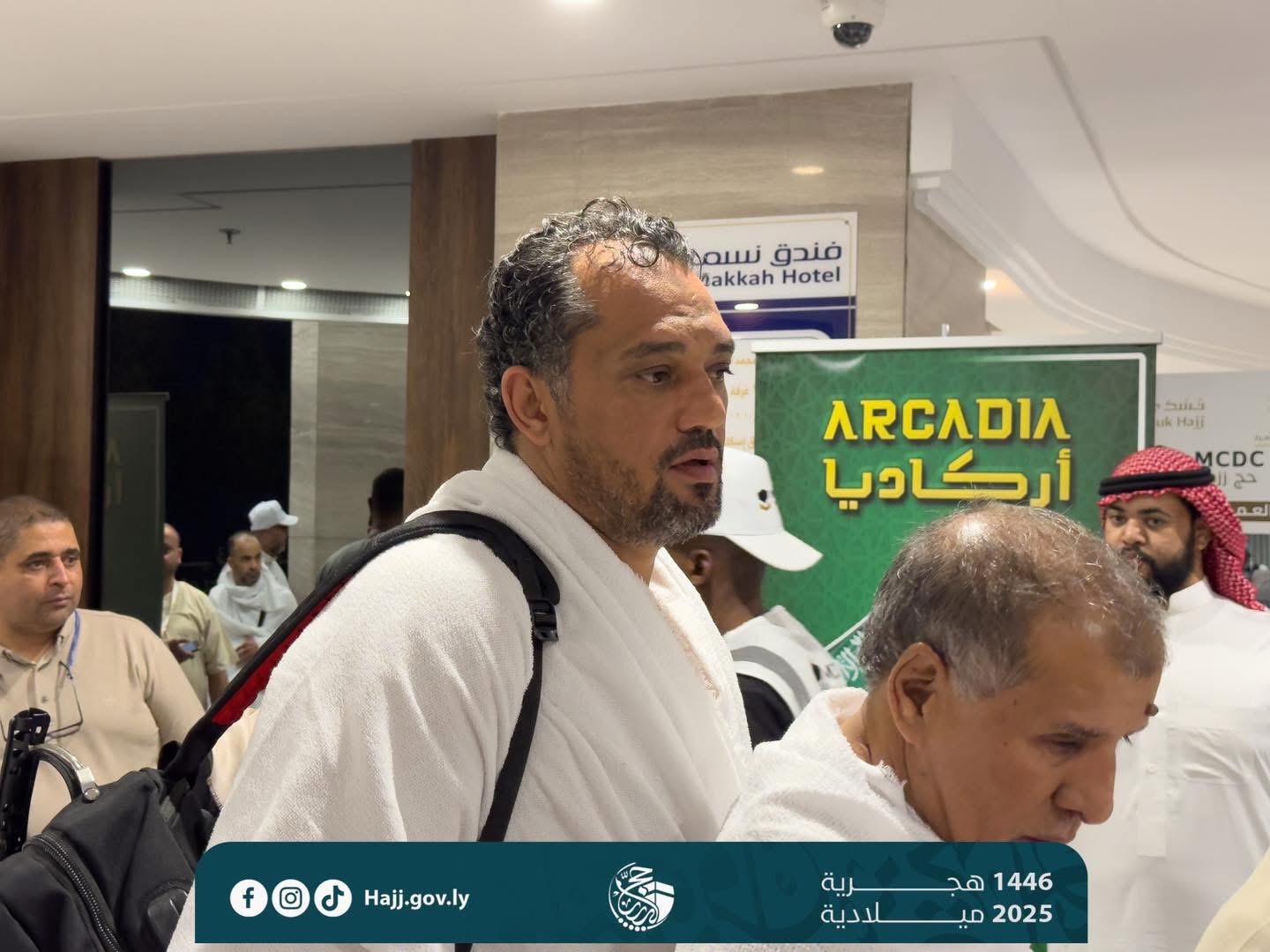 Person in ihram at Hajj with Arcadia banner